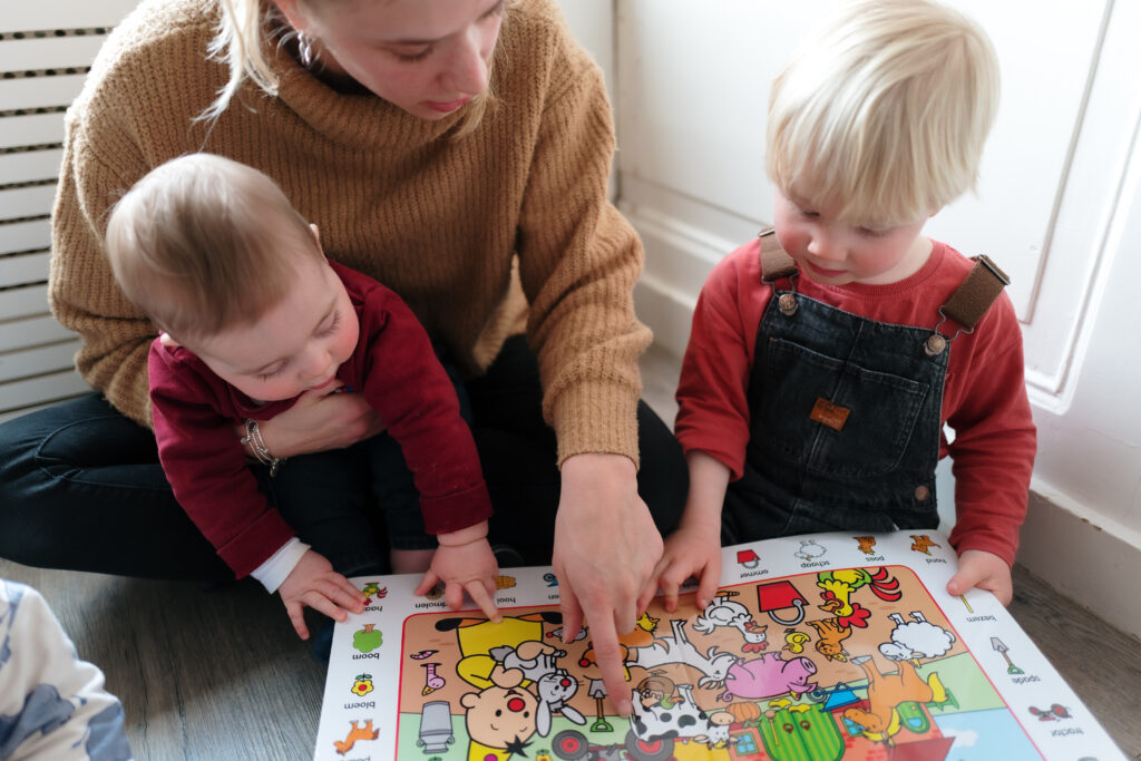 pedagogisch professional en kinderen lezen samen in een boekje