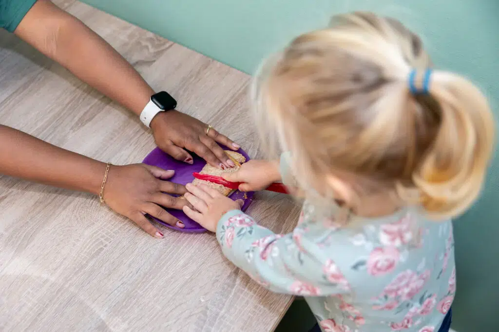 Meisje Snijdt Boterham Met Pedagogisch Medewerker 1024x683 1